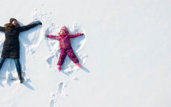 Adulte et enfant faisant des anges dans la neige